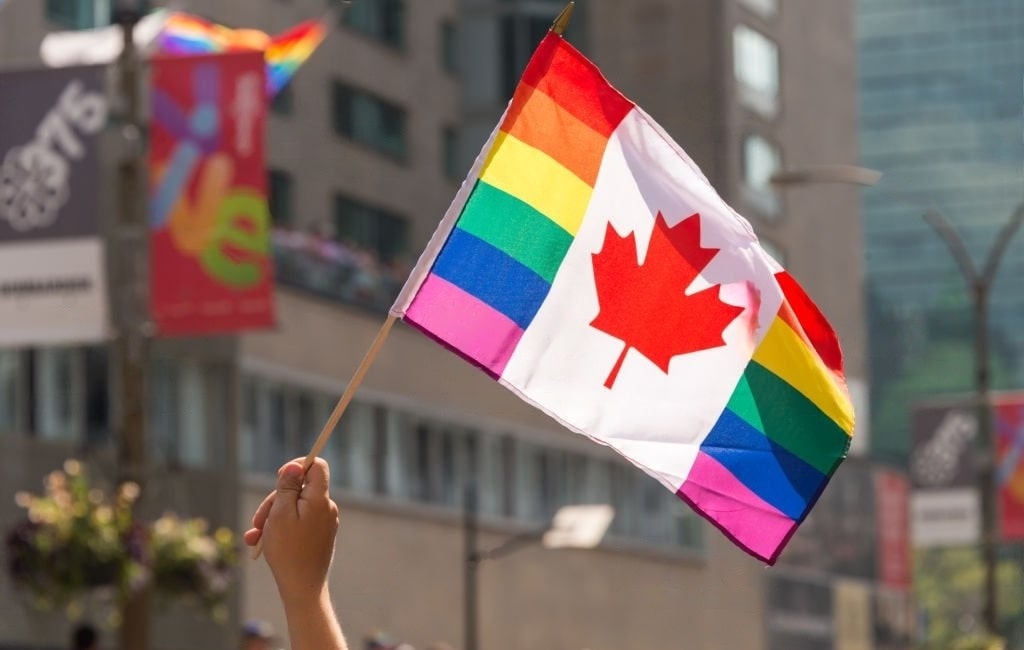 LGBTQ individuals celebrating diversity with Canadian flags, symbolizing inclusive immigration policies.
